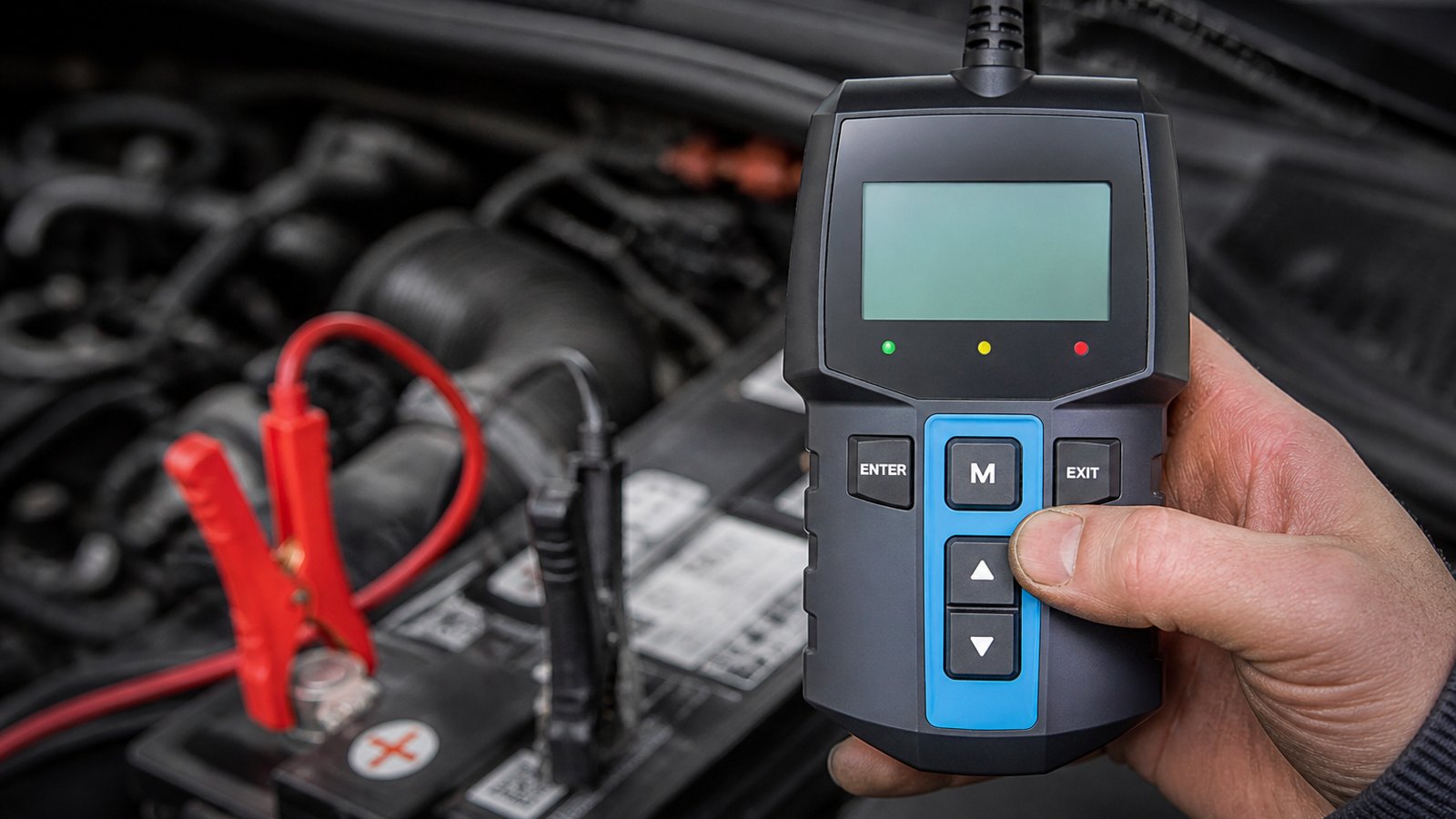 Handheld twelve-volt battery analyser in a UK garage scene